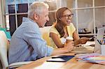 Creative business people laughing while looking at laptop