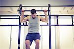 Fit man doing pull ups in fitness studio