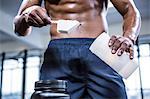 Fit shirtless man scooping protein powder