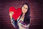 Attractive young woman holding up heart-shaped pillow