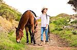 Young woman walking with her horse