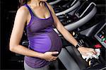 Pregnant woman touching belly on treadmill