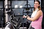 Pregnant woman riding bike looking at her smart watch