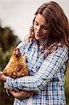 Woman holding and looking at chicken