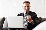 Smiling businessman using laptop and smartphone