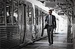 A working day. Businessman in a work suit and tie walking on the platform by a train carriage.