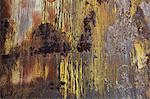 A wall with paint drips and marks and rust stains on metal.