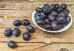 Plate full of fresh plums on a wooden background