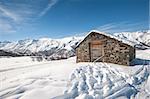 Remote stone mountain hut on an alpine slope covered in snow
