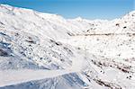 View down a snowy ski piste in alpine mountain valley