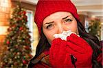 Sick Mixed Race Woman Blowing Her Sore Nose With Tissue In Christmas Setting.