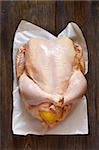 Fresh raw whole chicken stuffed lemon for cooking on wooden board. Top view.