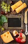 Delicious cheese with fruit and nuts and chalk blackboard for text on a wooden board. Vintage style.