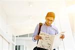 Asian Indian businessman reading newspaper on the way to work in a morning. Handsome male model.