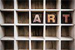 The word "ART" written in vintage ink stained wooden letterpress type in a partitioned printer's drawer.