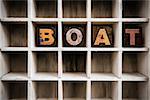 The word "BOAT" written in vintage ink stained wooden letterpress type in a partitioned printer's drawer.