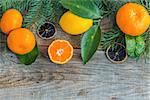 Tangerines, lemons and spruce branches on a wooden background.