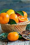 Basket with citrus and spruce branches on a wooden table.