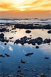 reflections at rocky beach near ballybunion on the wild atlantic way ireland with a beautiful yellow sunset