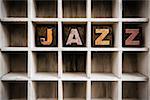 The word "JAZZ" written in vintage ink stained wooden letterpress type in a partitioned printer's drawer.