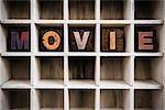 The word "MOVIE" written in vintage ink stained wooden letterpress type in a partitioned printer's drawer.