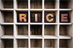 The word "RICE" written in vintage ink stained wooden letterpress type in a partitioned printer's drawer.