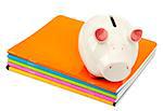 Piggy bank on pile of copybooks on isolated white background