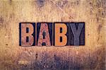 The word "Baby" written in dirty vintage letterpress type on a aged wooden background.
