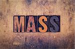 The word "Mass" written in dirty vintage letterpress type on a aged wooden background.