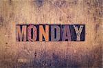 The word "Monday" written in dirty vintage letterpress type on a aged wooden background.