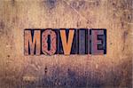 The word "Movie" written in dirty vintage letterpress type on a aged wooden background.