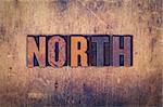 The word "North" written in dirty vintage letterpress type on a aged wooden background.