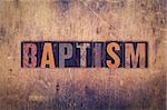 The word "Baptism" written in dirty vintage letterpress type on a aged wooden background.