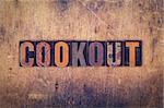 The word "Cookout" written in dirty vintage letterpress type on a aged wooden background.