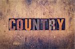 The word "Country" written in dirty vintage letterpress type on a aged wooden background.