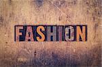 The word "Fashion" written in dirty vintage letterpress type on a aged wooden background.