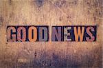 The word "Good News" written in dirty vintage letterpress type on a aged wooden background.