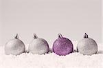 silver and purple decorative christmas balls on snow against grey background