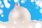 white decorative christmas ball on snow against blue festive background