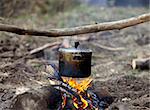 Cooking in sooty cauldron on campfire at forest