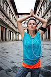 Now it is time to invest in your body and no matter you are at hometown or traveling. Fitness young woman with earphones doing yoga outdoors in front of Uffizi gallery in Florence Italy