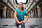Now it is time to invest in your body and no matter you are at hometown or traveling. Fitness woman in sporty outfit and mp3 set is stretching next to Uffizi gallery in Florence Italy