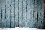 Old weathered wood plank fence and a ground covered with snow