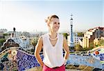 Refreshing promenade in unique Park Guell style in Barcelona, Spain. Happy young woman tourist in Park Guell, Barcelona, Spain looking into the distance