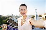 Refreshing promenade in unique Park Guell style in Barcelona, Spain. Happy young woman tourist taking selfie in Park Guell, Barcelona, Spain