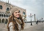 Delightful Venice, Italy can help make the most of your next winter getaway. Happy young woman tourist taking photos on St. Mark's Square near Dogi Palace