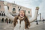 Delightful Venice, Italy can help make the most of your next winter getaway. Happy young woman tourist rejoicing on St. Mark's Square near Dogi Palace