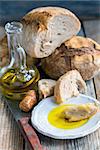Plate with olive oil and homemade bread on an old wooden table.