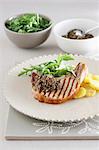 A grilled chop with potato and rocket salad