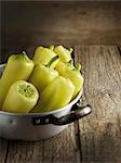 Yellow pointed peppers in an aluminium pot on a wooden table